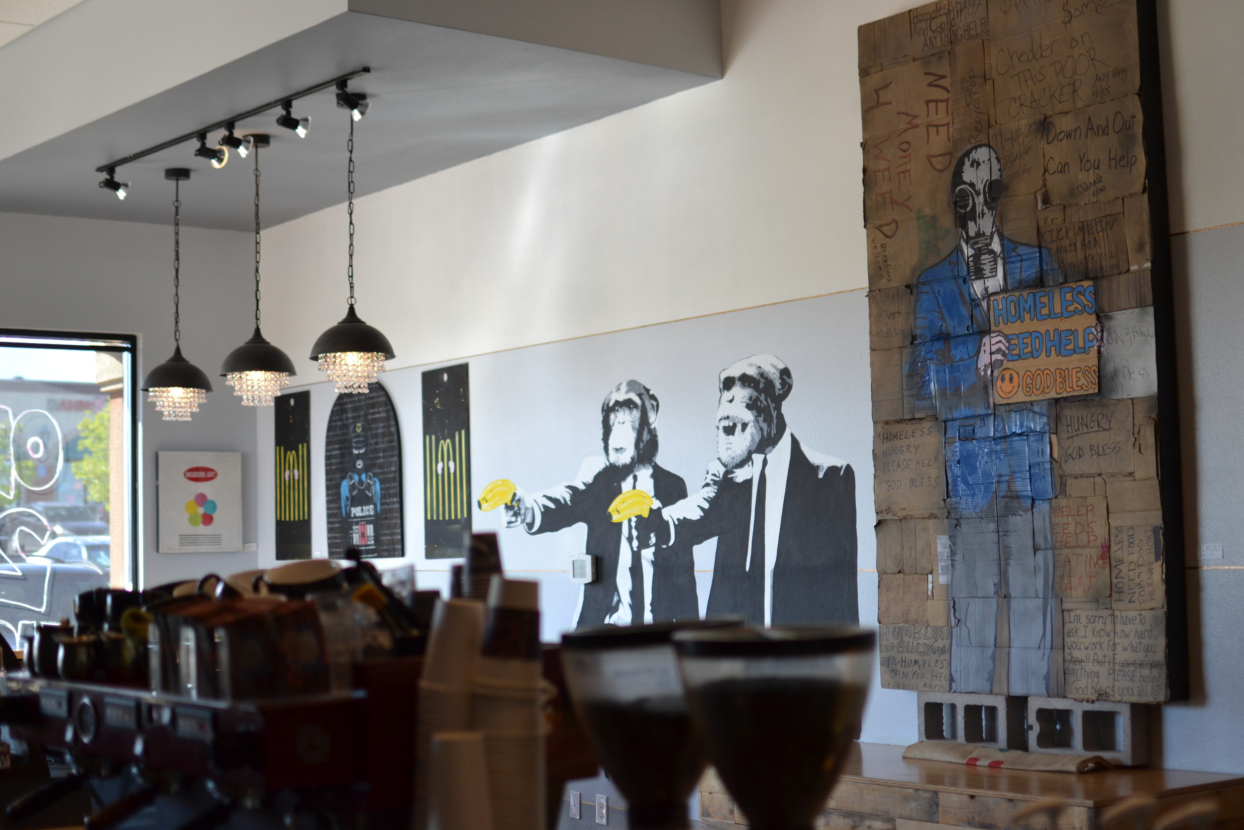 Two suited monkeys holding bananas painted on the Madhouse café wall, alongside other artwork